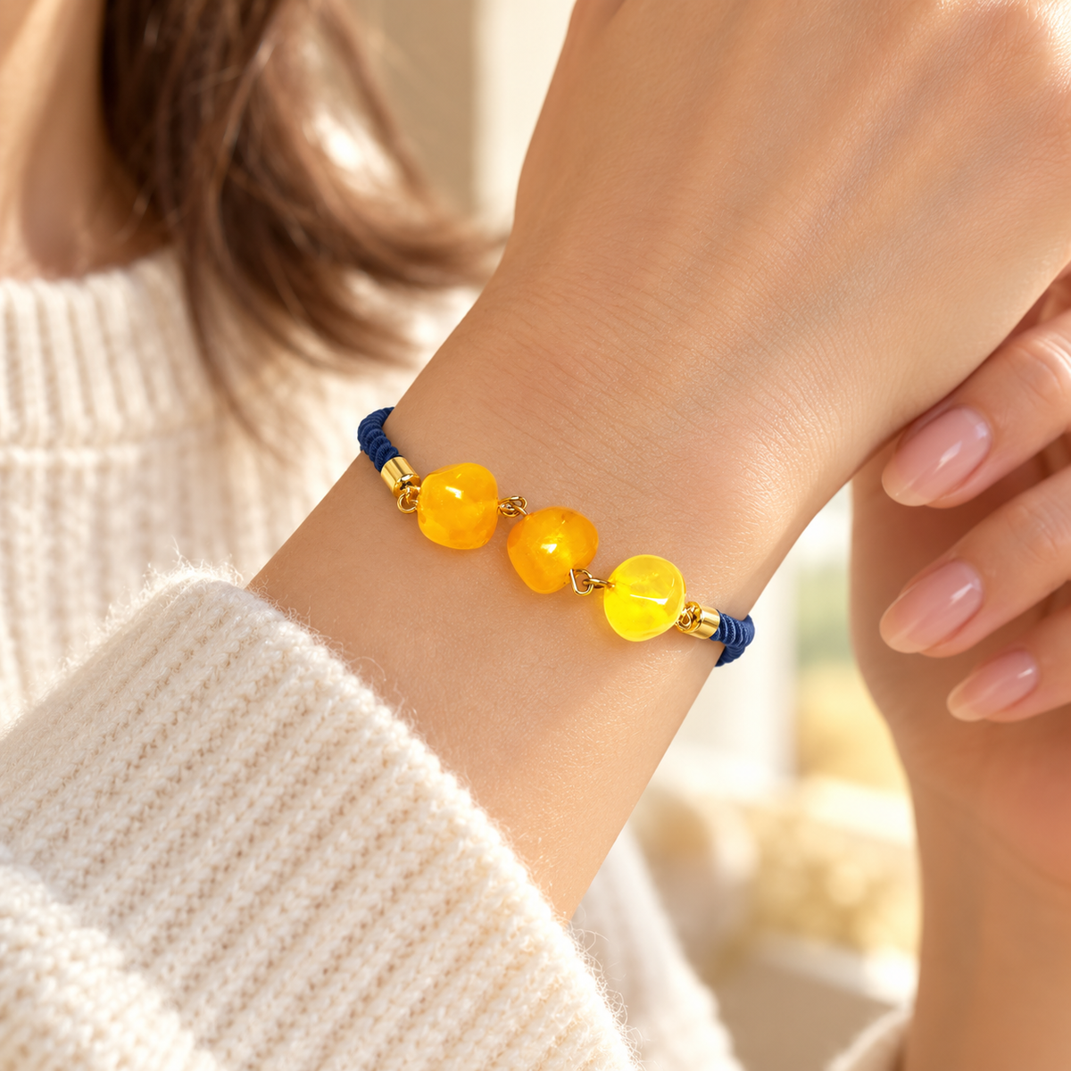KIZIMA 3P0500q5.73 bracelet with three yellow amber beads and navy cord worn on a woman's wrist