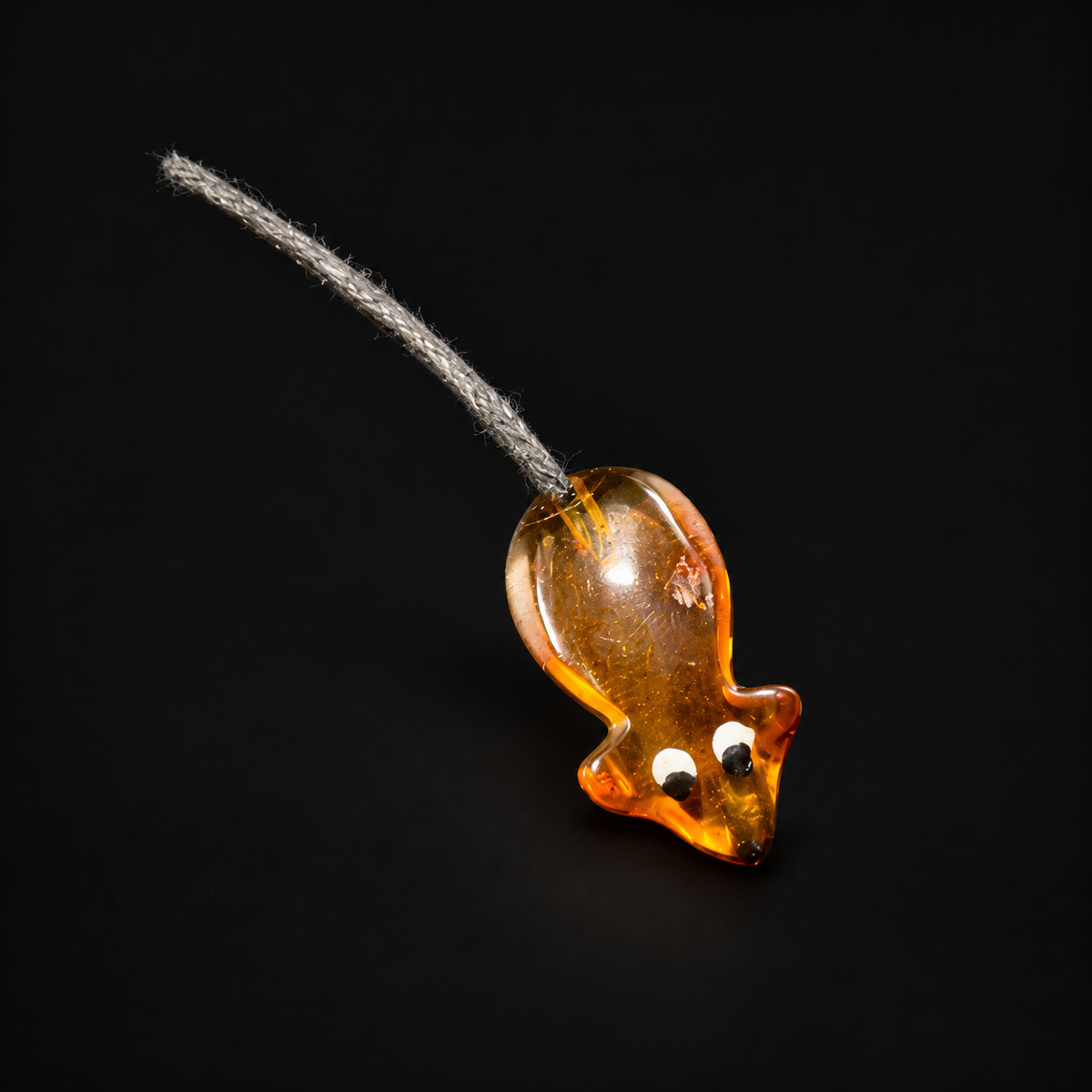 Made in USA Natural Baltic Amber money mouse amulet by KIZIMA®, cognac amber with painted eyes and gray cord tail, black studio background