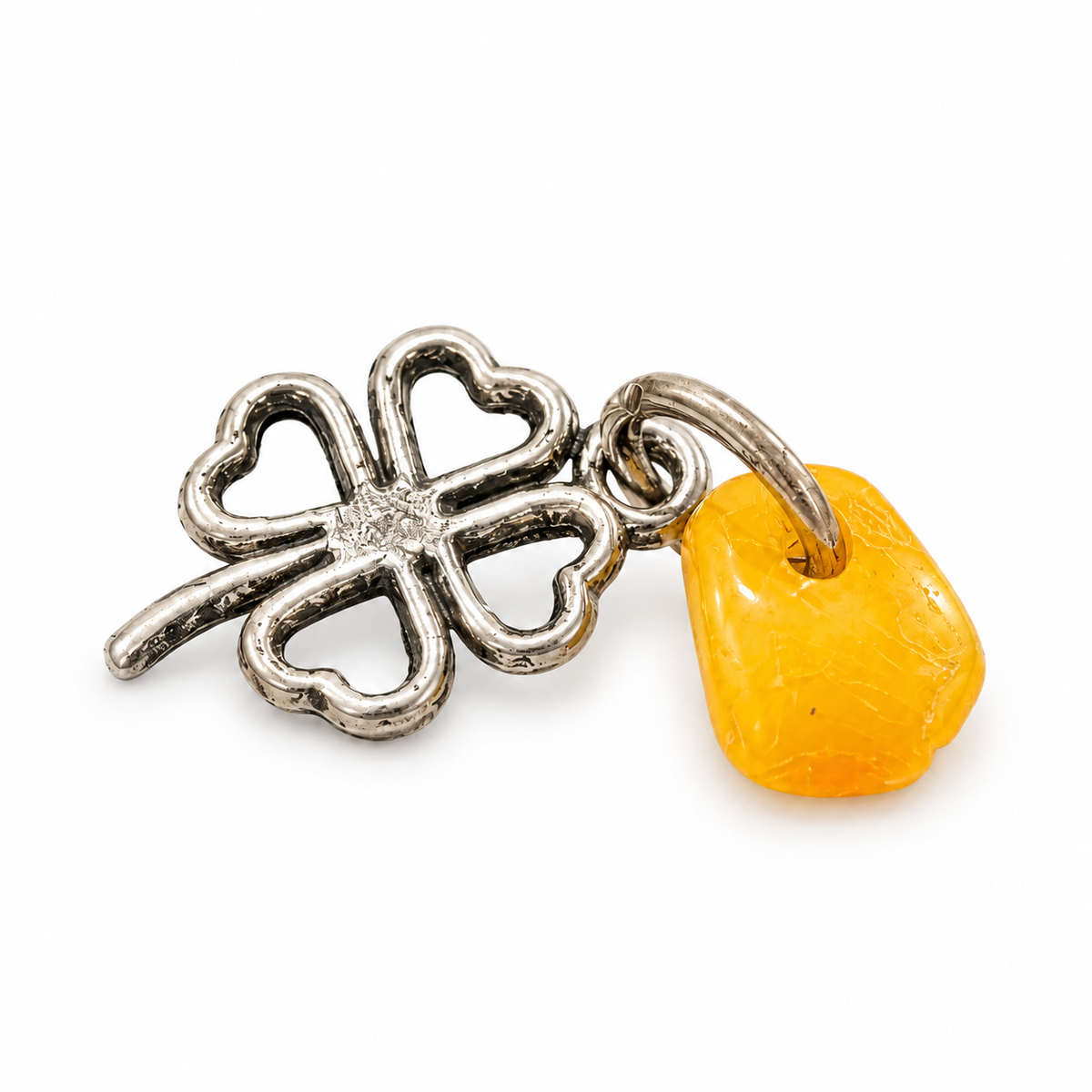 Metal four-leaf clover amulet with natural yellow Baltic amber on a white background