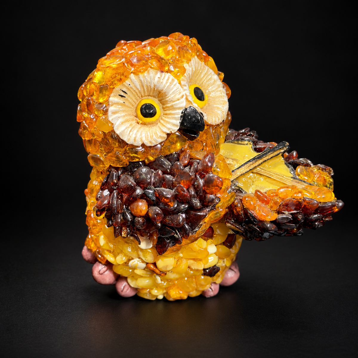 Amber mosaic owl playing a violin, golden-yellow and brown amber, on a black studio background.