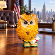 Made in USA natural Baltic amber graduate owl on a green book with a red-ribbon diploma, on an office desk.
