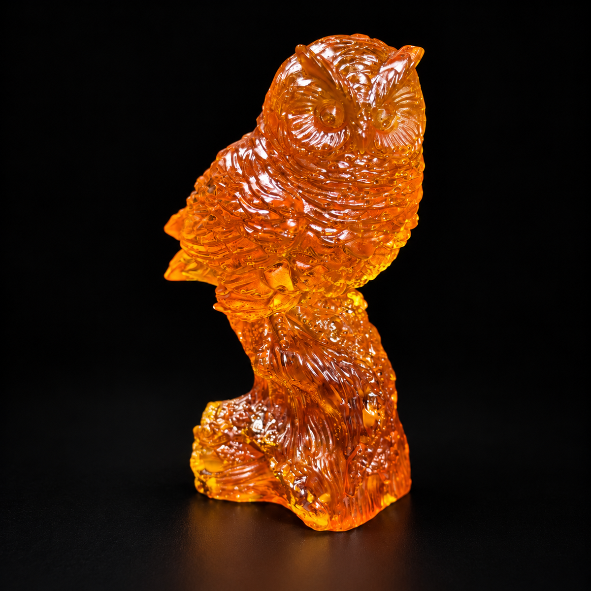 Orange owl figurine with detailed feathers and integral trunk base against a black studio background