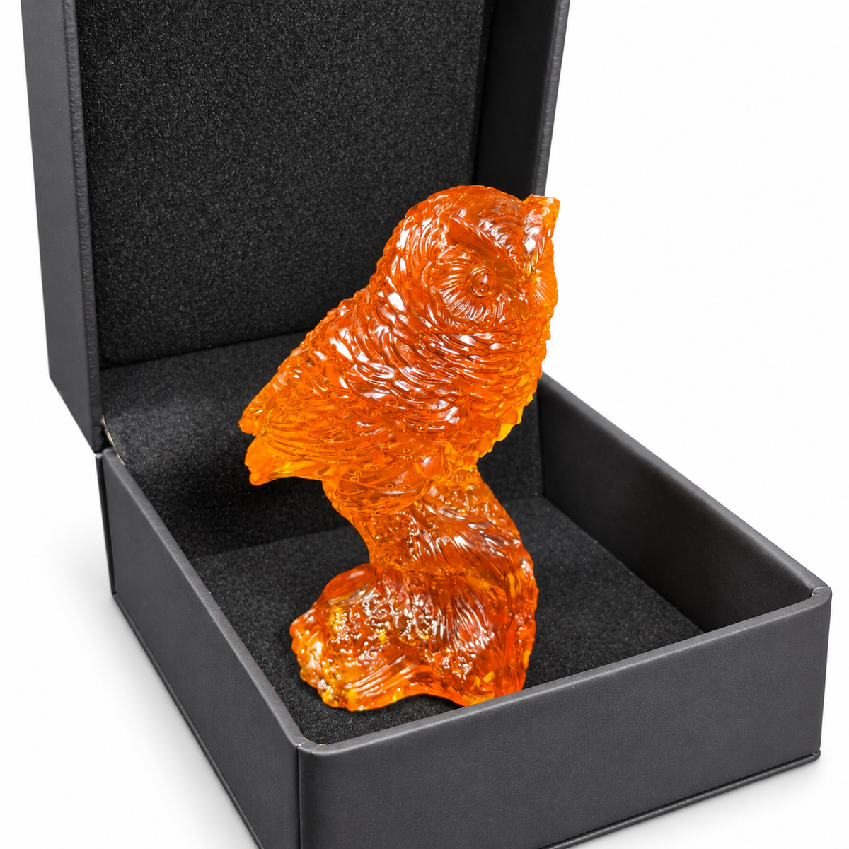 Orange owl figurine standing in its open black foam-lined presentation box on white