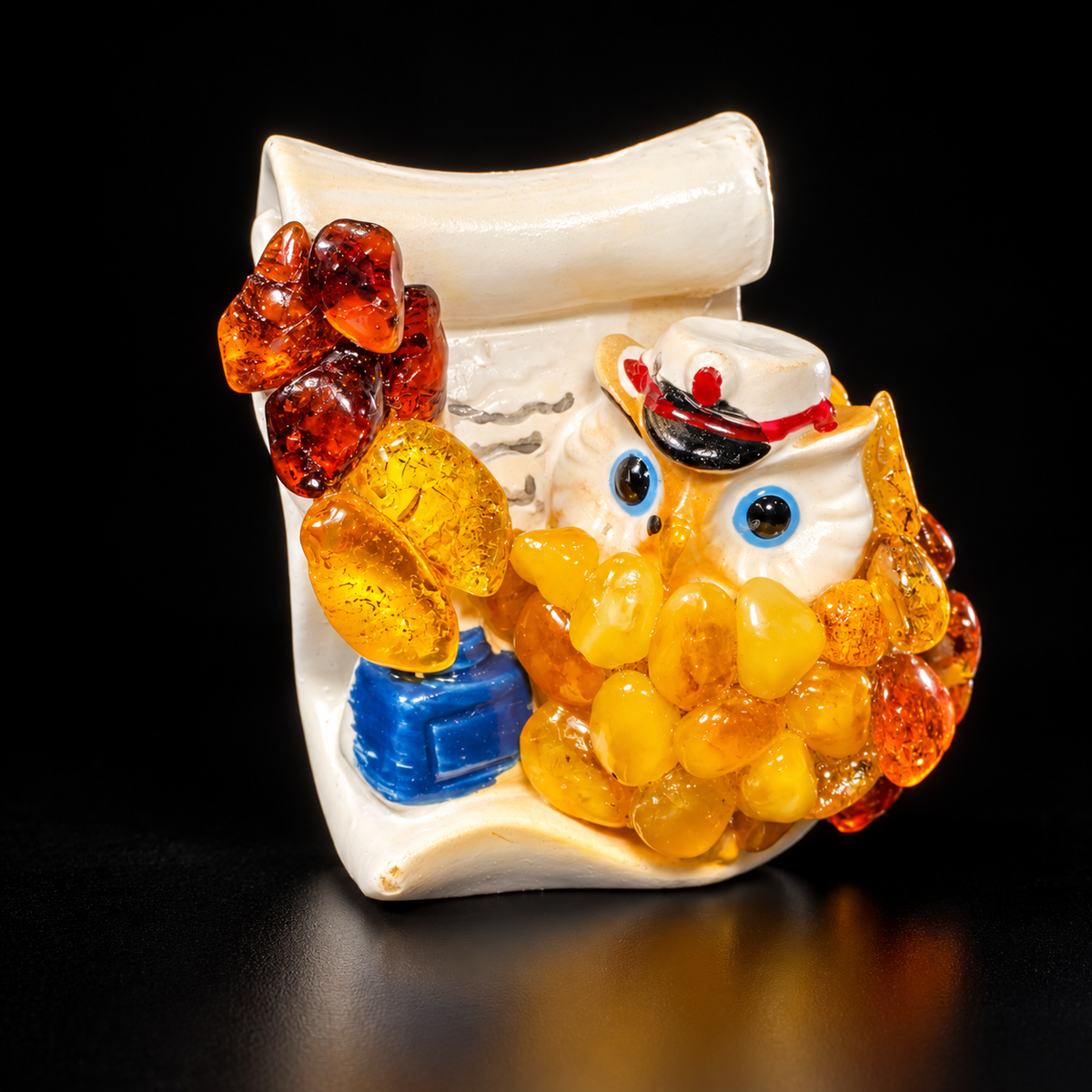 Honey-yellow and orange owl figurine with a cream scroll backing against a black studio background
