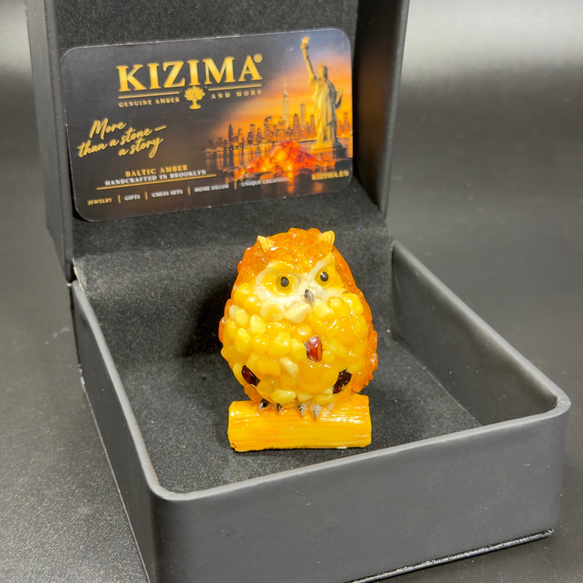 Original photograph of the yellow owl figurine in its black KIZIMA box