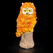 Made in USA natural Baltic amber owl on a carved tree stump, orange and golden mosaic, black studio background