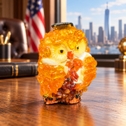 Made in USA natural Baltic amber mini owl in a dark cap on an oak desk with a US flag and Manhattan skyline.