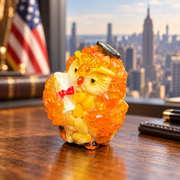 Made in USA natural Baltic amber mini graduation owl holding a diploma on an oak desk with a Manhattan skyline.