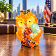Made in USA natural Baltic amber mini scholar owl holding a mint-green globe on an oak desk with a Manhattan skyline.