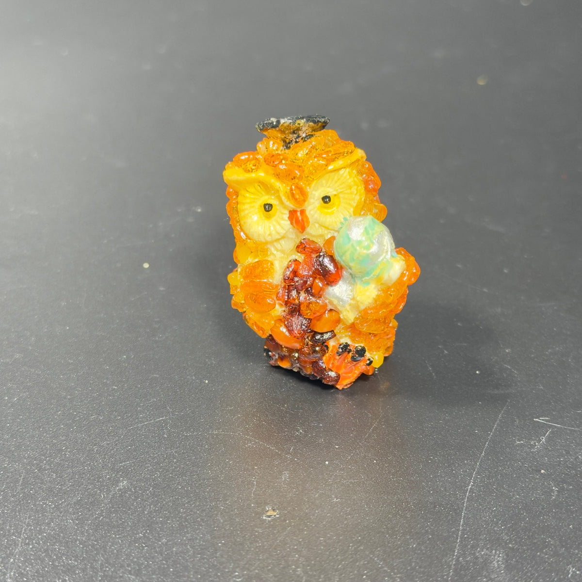 Original closeup photograph of golden orange owl holding a mint green globe