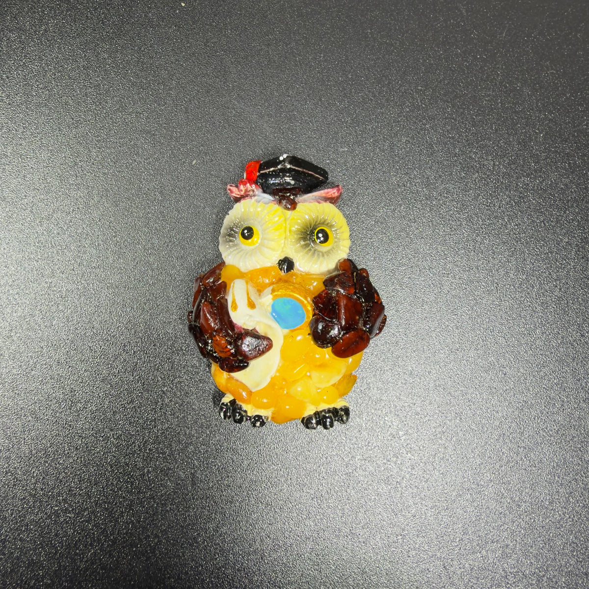 Original photograph of the yellow graduation owl magnet on a dark textured surface