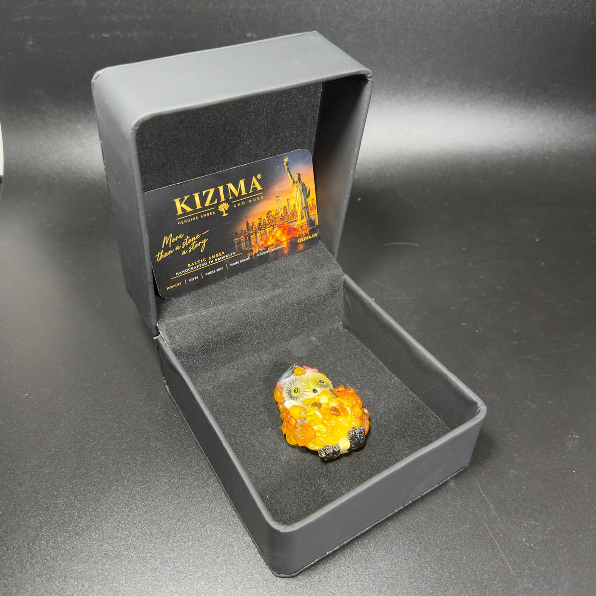 Unedited photo of the amber graduation owl magnet next to its KIZIMA packaging
