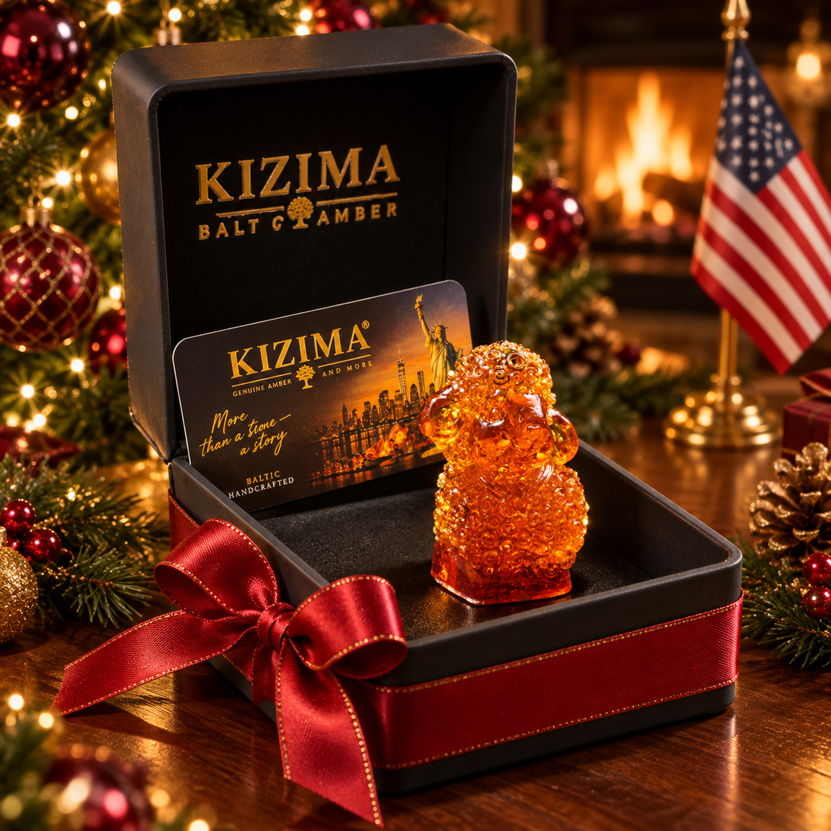Curly amber lamb with a pendant in an open black KIZIMA box, finished with a red satin bow beside a Christmas tree and American flag.