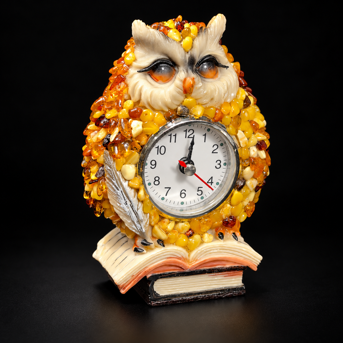 Front view of the amber owl clock with ivory dial and sculpted book base on a black studio background.