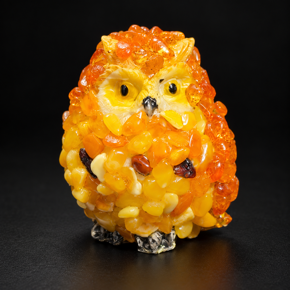 Orange and yellow owl figurine against a black studio background