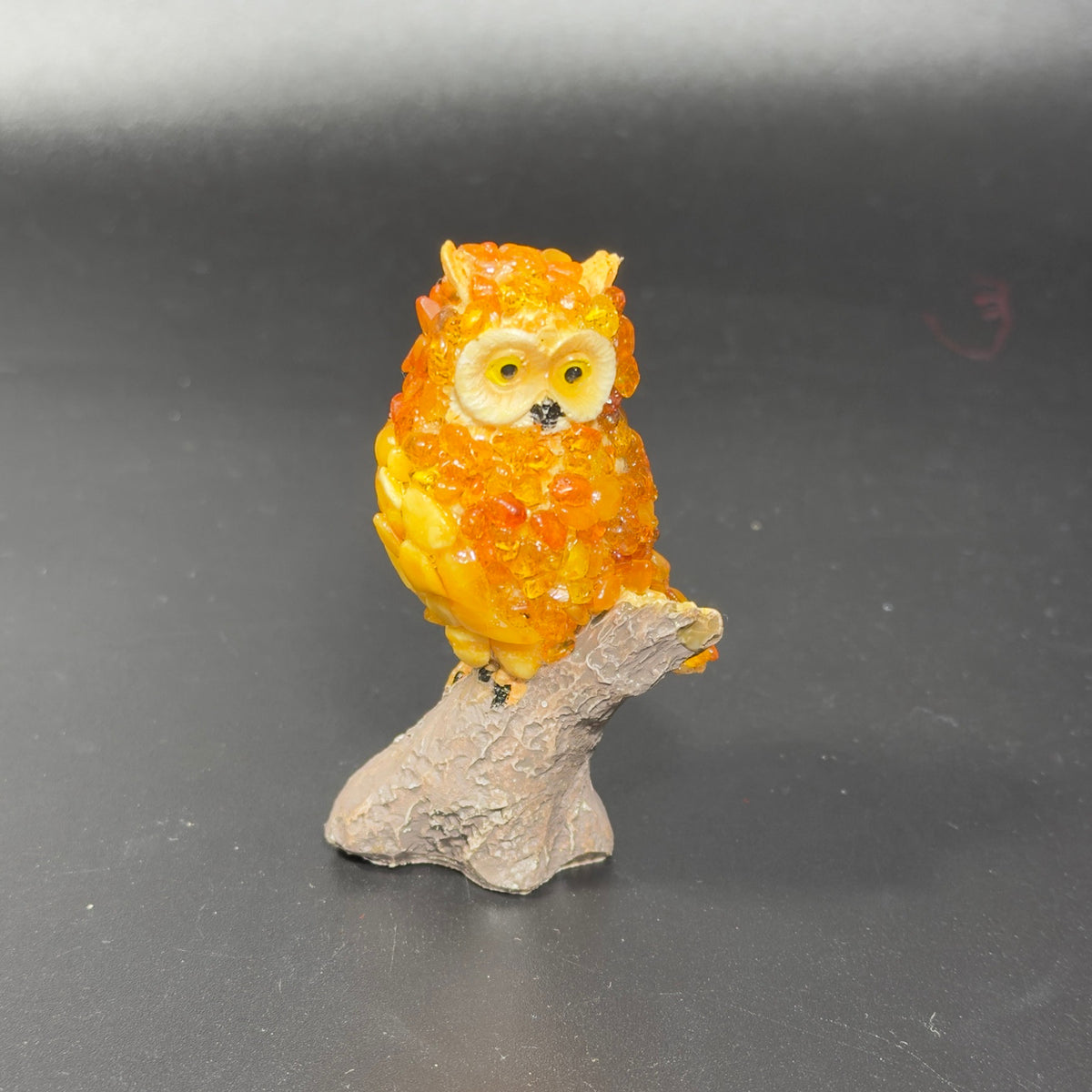 Original photograph of golden-orange owl figurine OWL24 on a gray-beige branch stand