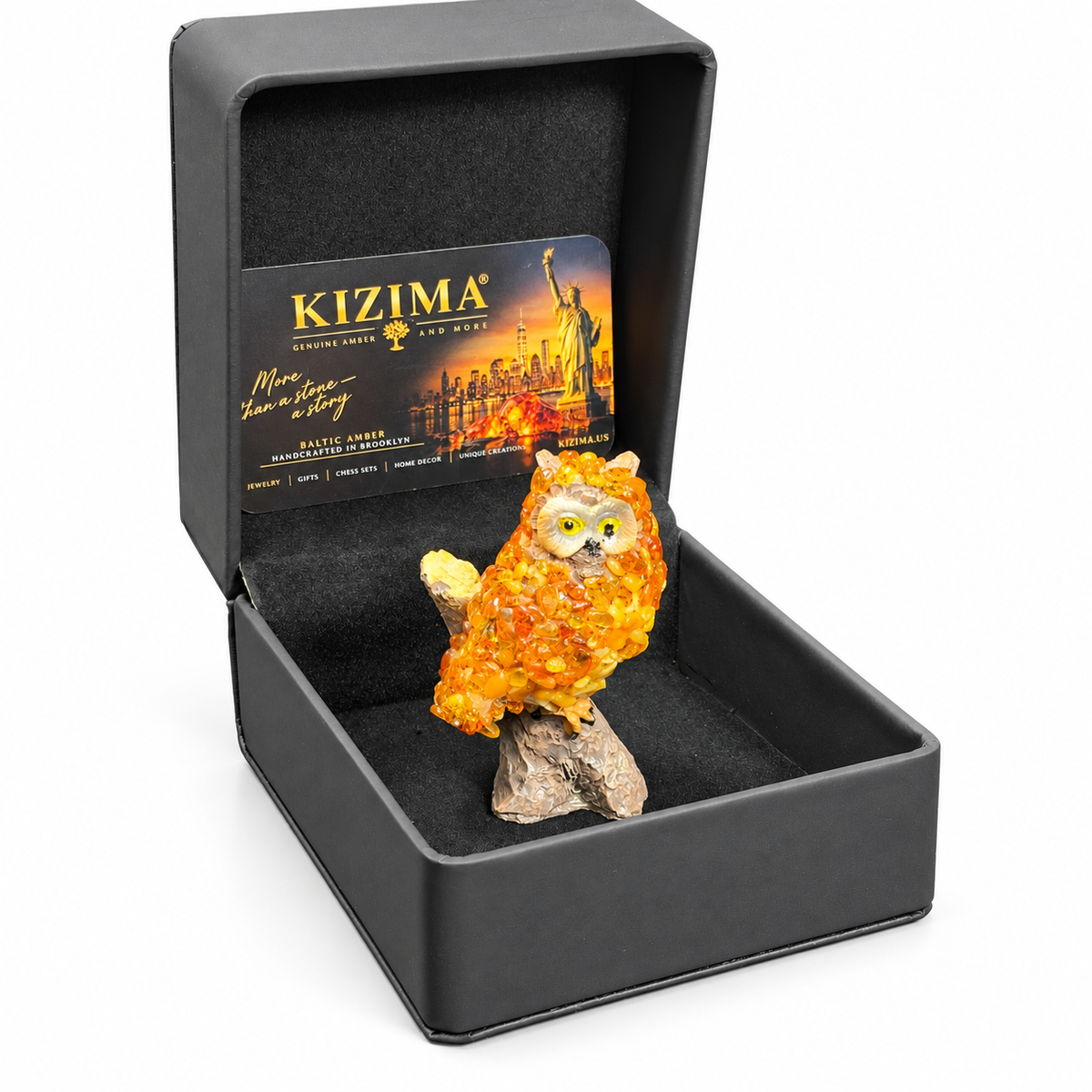 Golden orange owl figurine in its open black KIZIMA presentation box on white