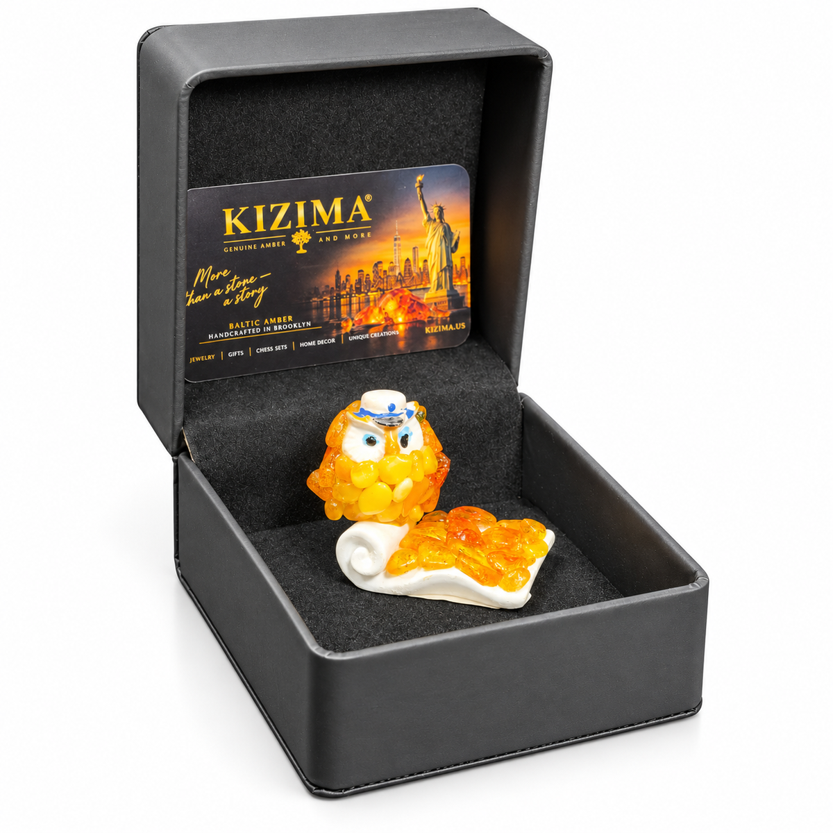 Golden-yellow owl in its open dark gray KIZIMA presentation box with branded card on a white background
