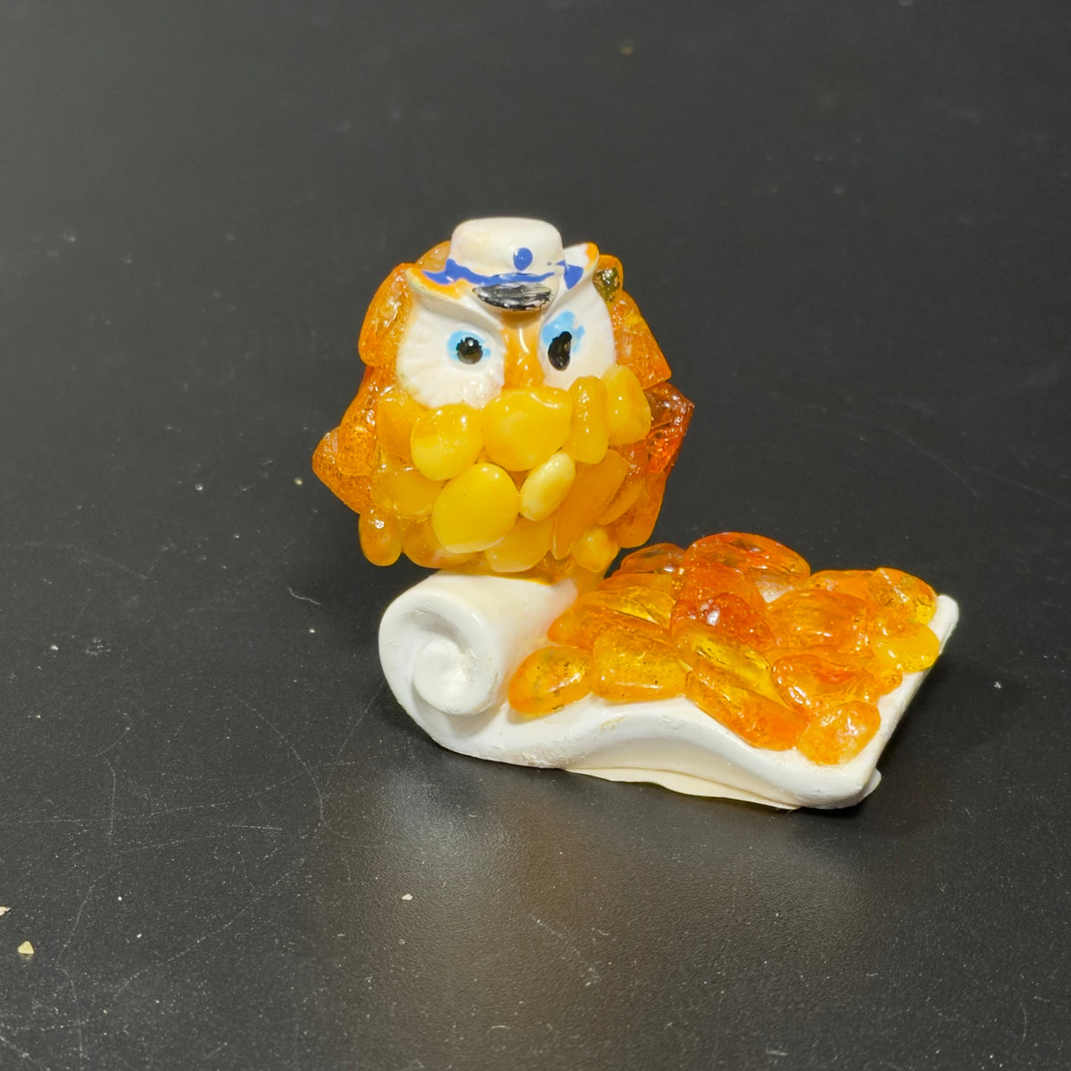 Original photo of the golden-yellow owl with white and blue hat and curled white scroll base