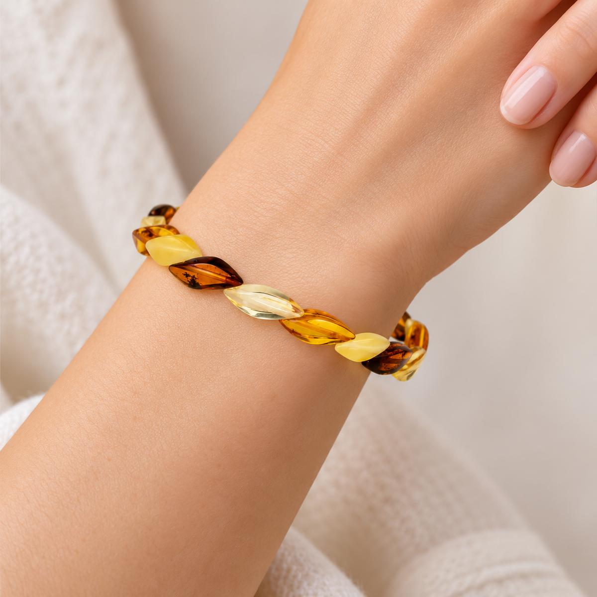 KIZIMA 5598877.1 nineteen-leaf multicolor Baltic amber bracelet worn on a young adult woman's wrist.