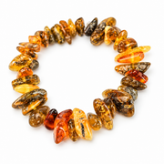 Irregular honey, cognac and olive amber nuggets with dark inclusions on pure white.