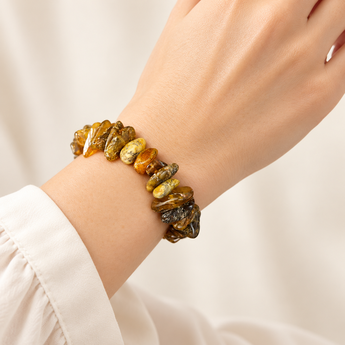 Irregular polished amber nugget bracelet on a young adult woman's graceful wrist.