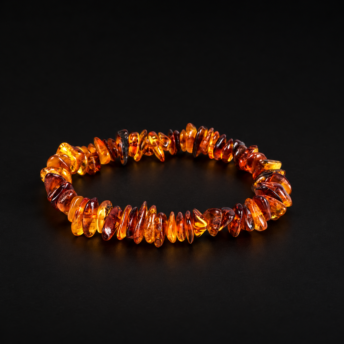 KIZIMA polished honey and cognac amber chip bracelet on a black studio background.