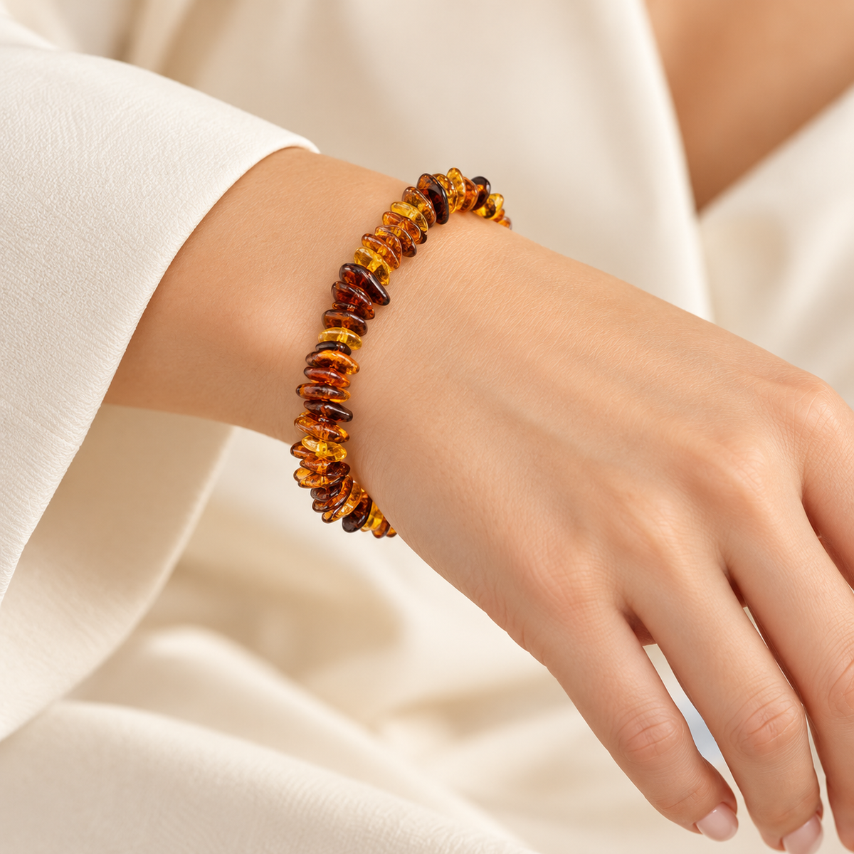 KIZIMA polished honey and cognac amber chip bracelet on a young adult woman's wrist.