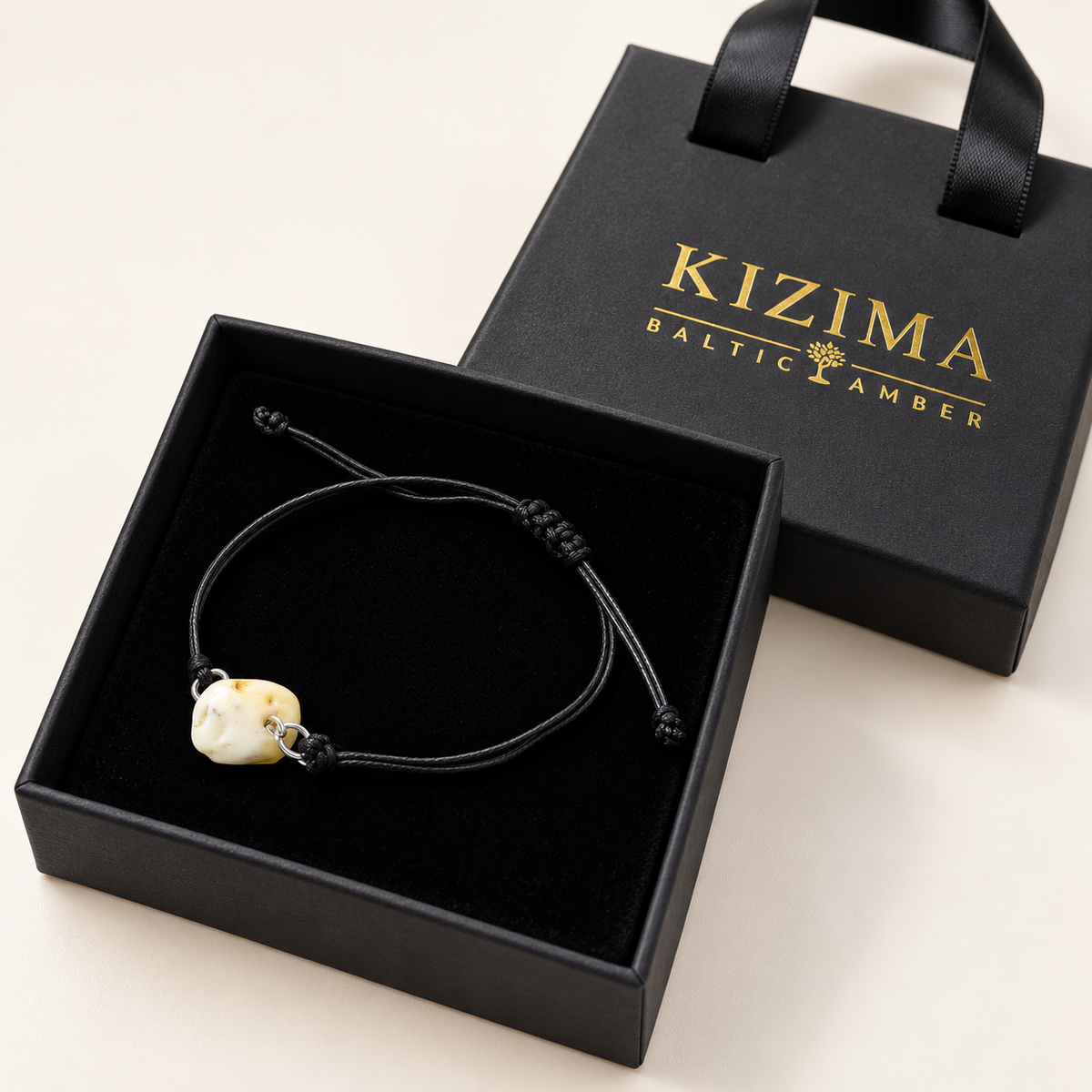 KIZIMA cream amber nugget on adjustable black cord bracelet in a KIZIMA gift box.