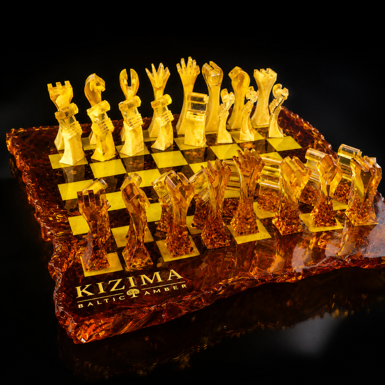 KIZIMA® handcrafted Baltic amber chess set with sculptural modern chess pieces and artistic irregular amber board design in glowing honey and cognac tones on a black background.
