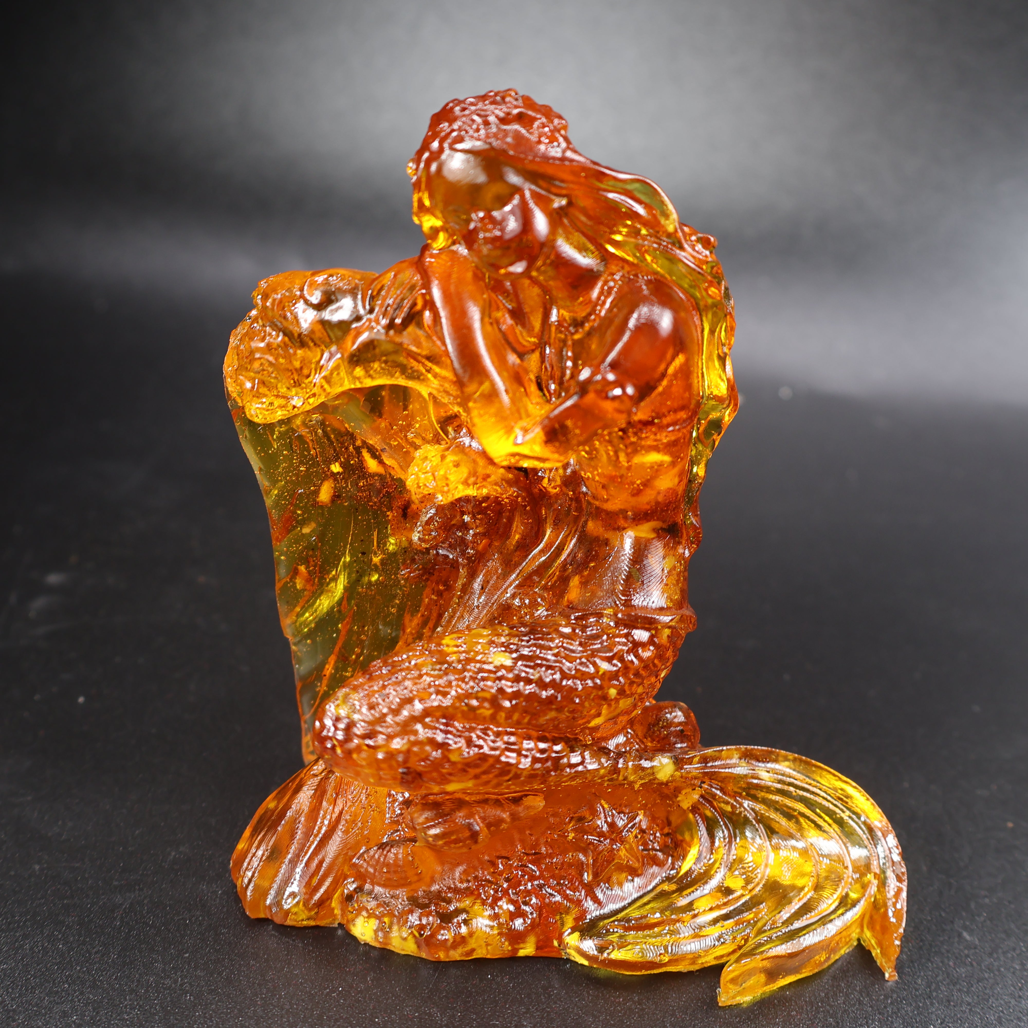 Detail view of hand-carved Baltic amber mermaid tail and sea wave base