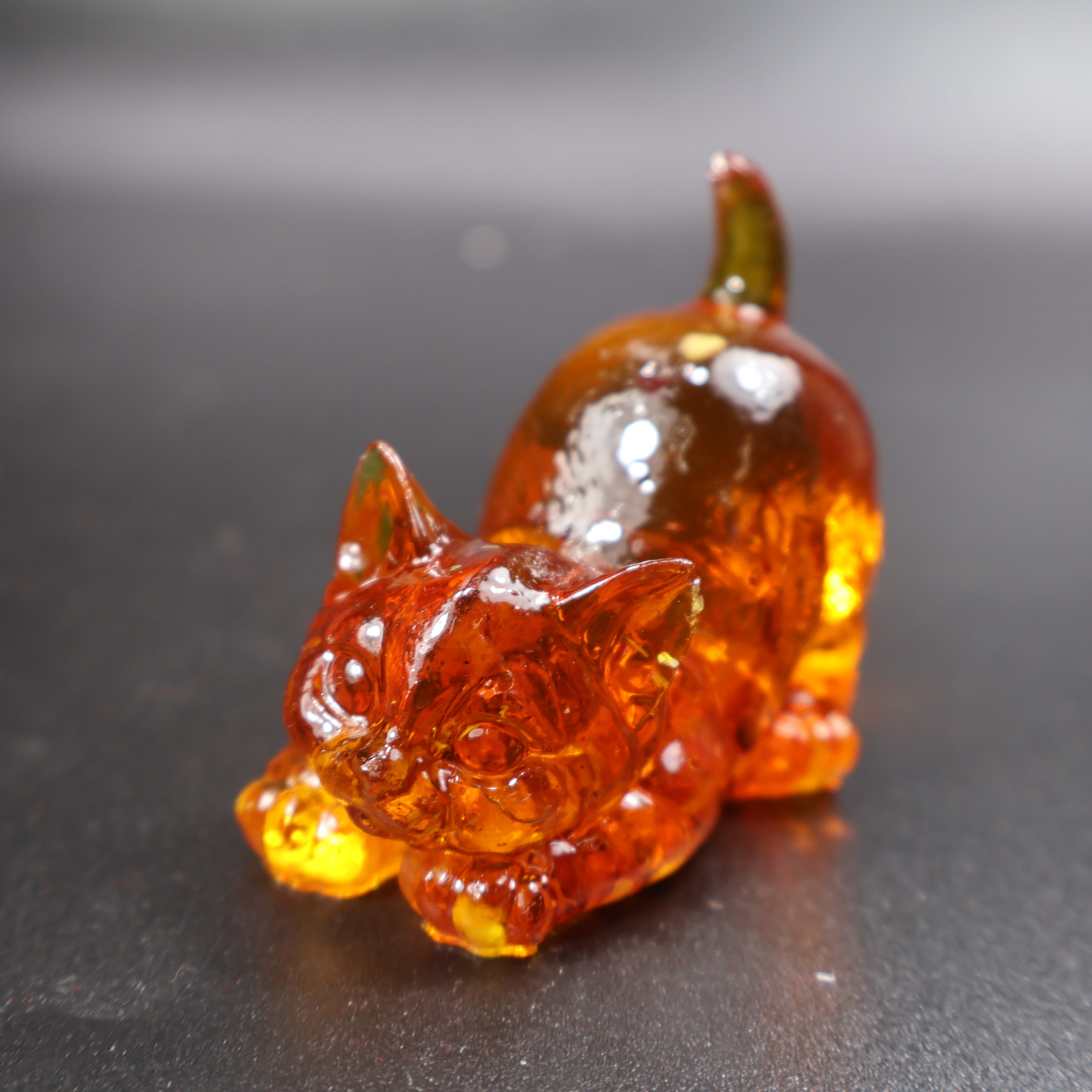 Natural Baltic amber cat figurine showing golden-brown amber grain, close-up