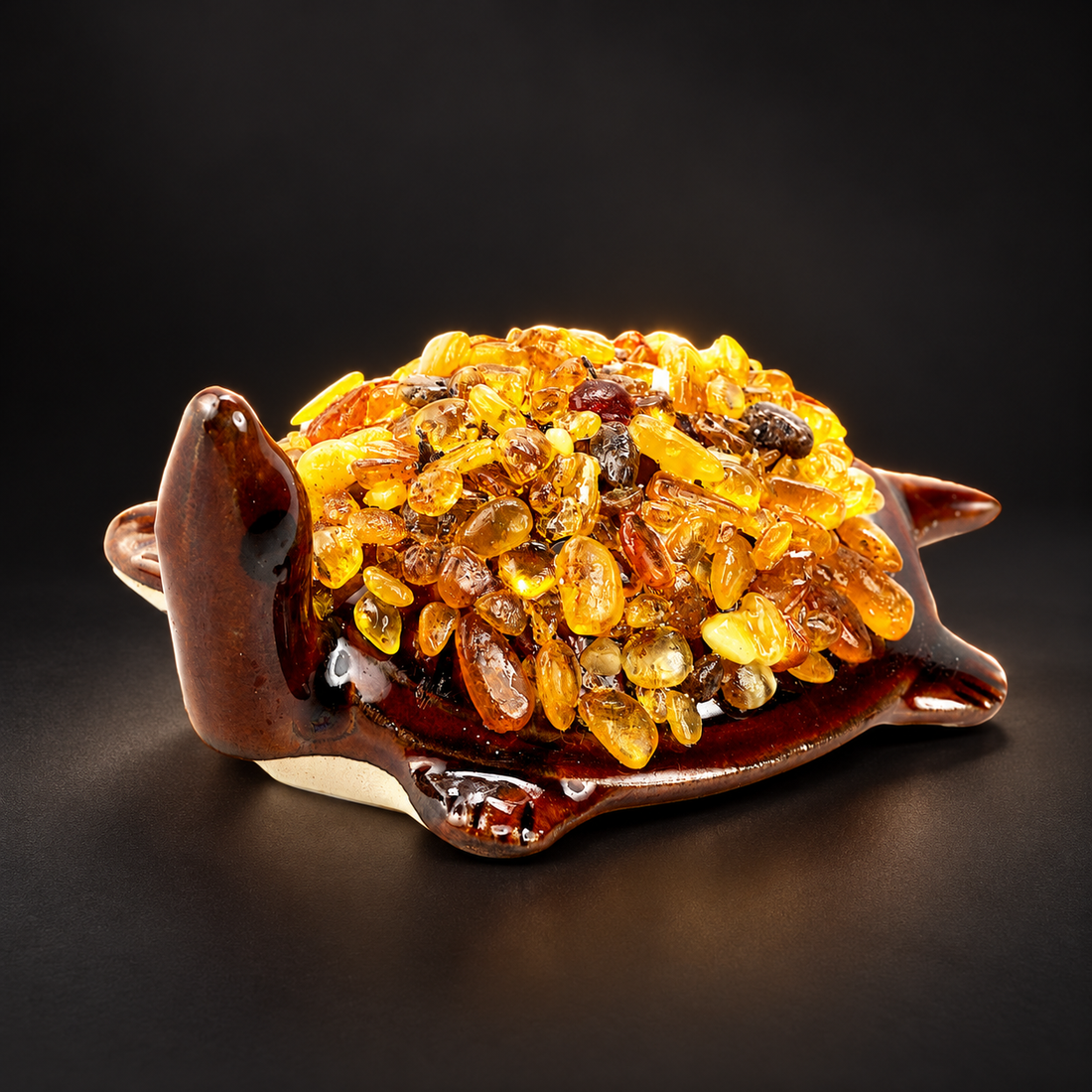 KIZIMA 10N0050q21 Baltic amber turtle figurine on a black studio background, showing the brown ceramic body and natural amber-chip shell.