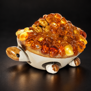 KIZIMA 10Z0100q53 Baltic amber turtle figurine on a black studio background, showing the cream ceramic movable body and golden amber pebble shell.