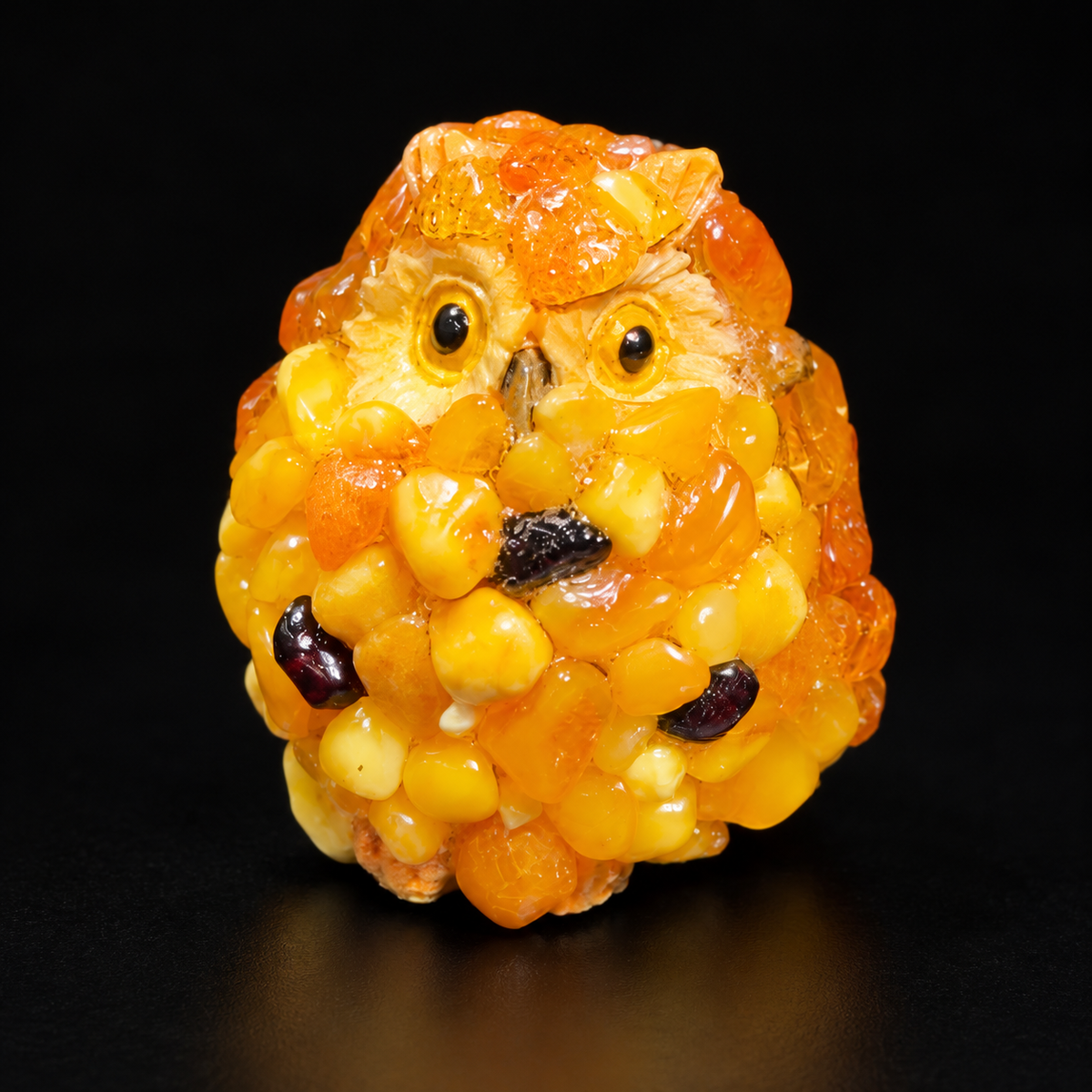 Golden yellow and orange amber mini owl with dark accents against a black studio backdrop.