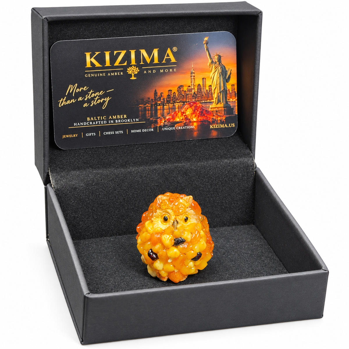 Tiny amber owl figurine in an open black presentation box with KIZIMA card on white.