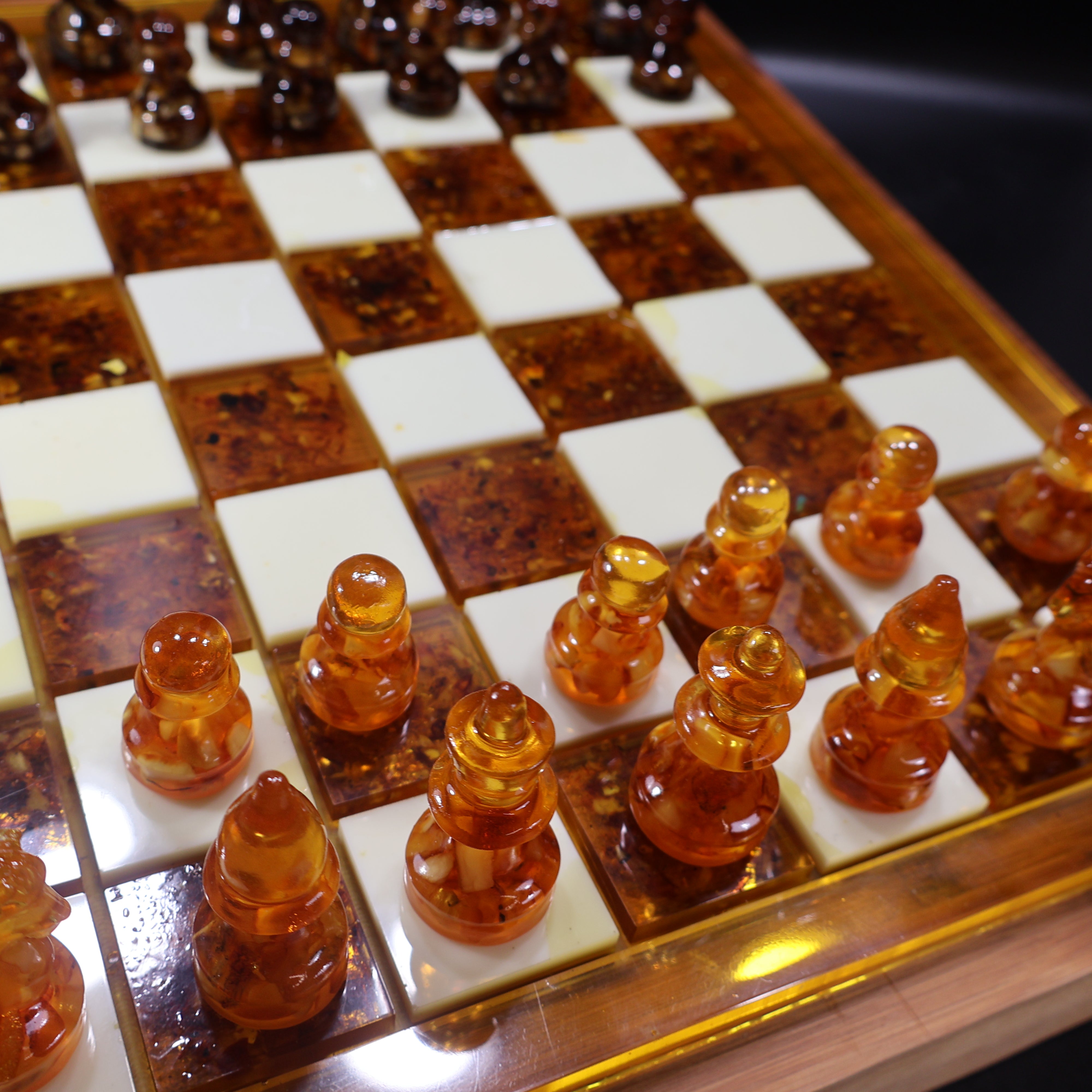 Wooden chess board edge detail with brass trim and amber inlay squares