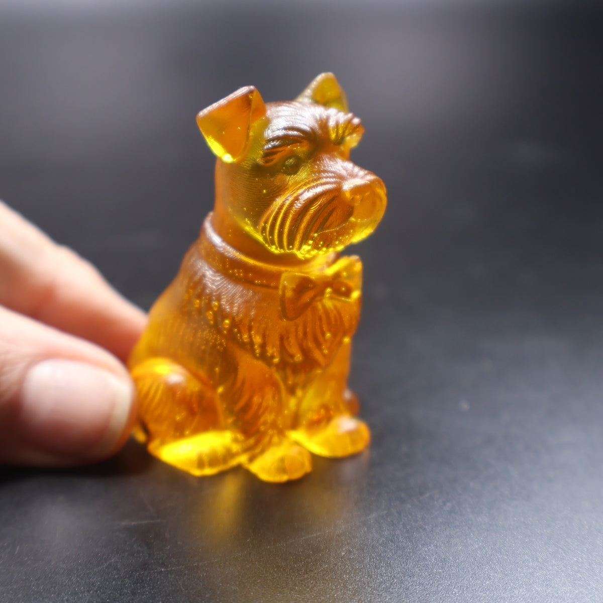 Baltic amber Schnauzer figurine held in hand showing miniature size, KIZIMA gift