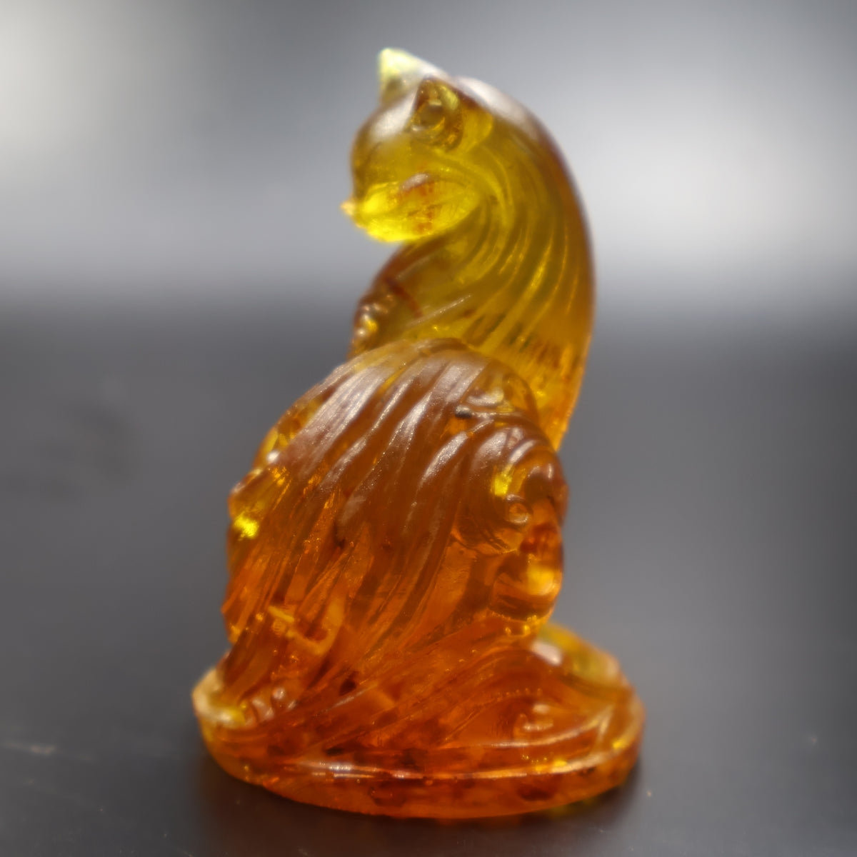 Amber ornamental cat figurine back view showing tail carving, American amber decor
