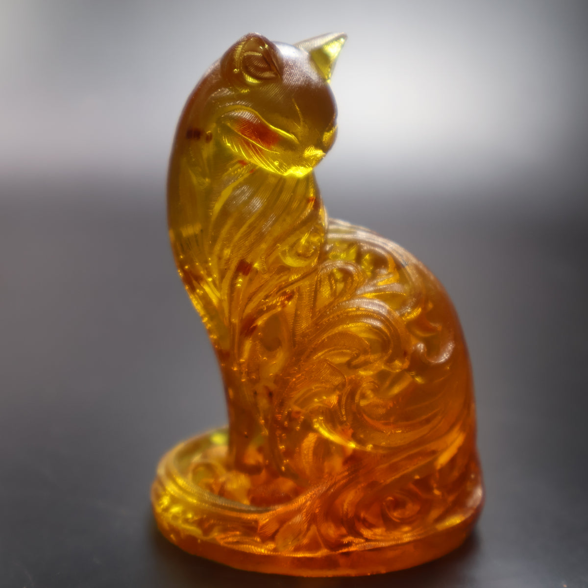 Amber cat sculpture with carved swirls catching light, collectible by KIZIMA USA