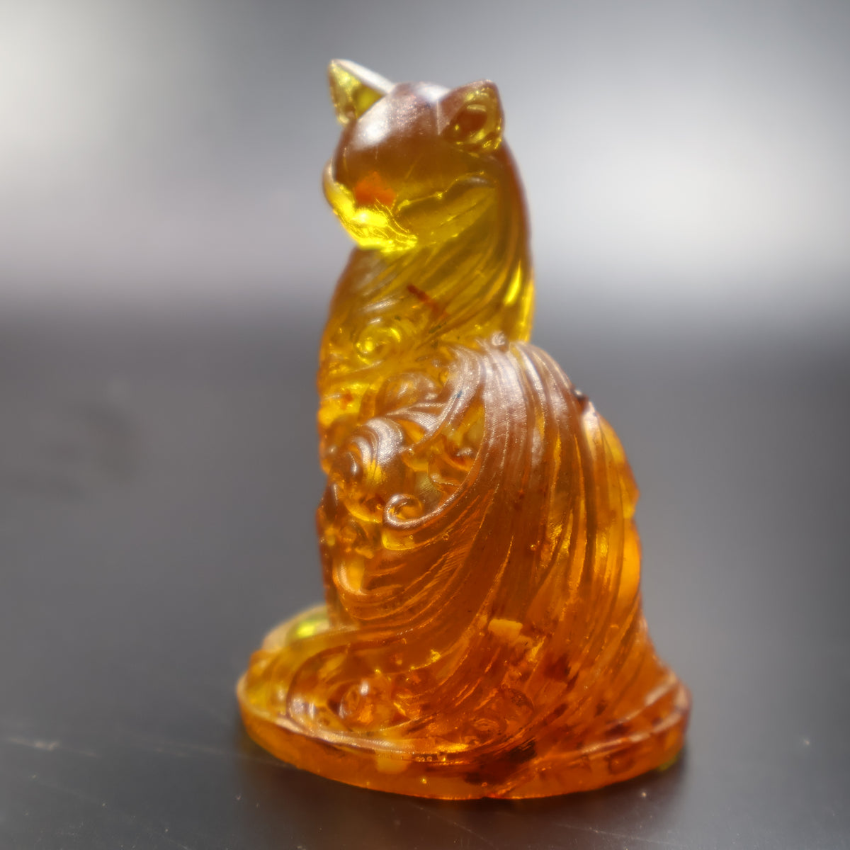 Baltic amber seated cat miniature sculpture with flowing carved ornament, honey gold