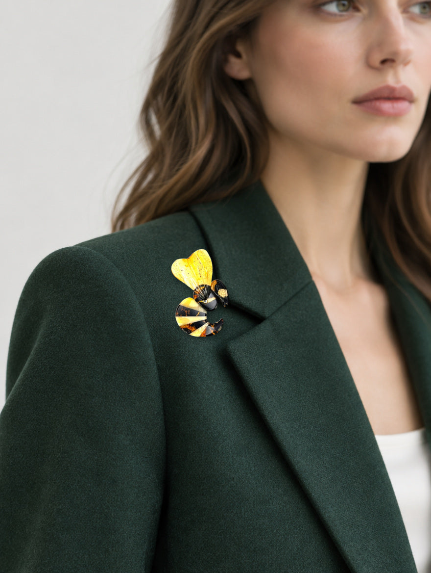 Woman wearing KIZIMA® Natural Baltic Amber wasp brooch on a green blazer lapel — handmade nature jewelry gift for her
