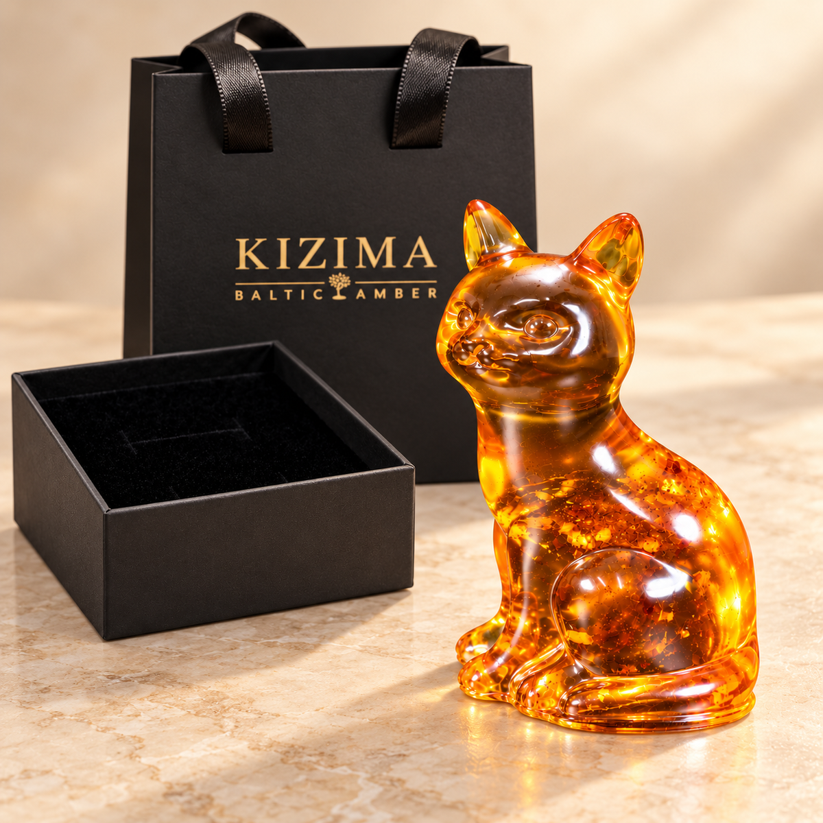 KIZIMA cognac amber sitting cat beside its black velvet-lined gift box and KIZIMA Baltic Amber gift bag