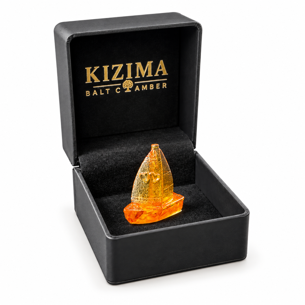 Miniature amber sailboat presented in an open black KIZIMA gift box with gold branding against a white background.