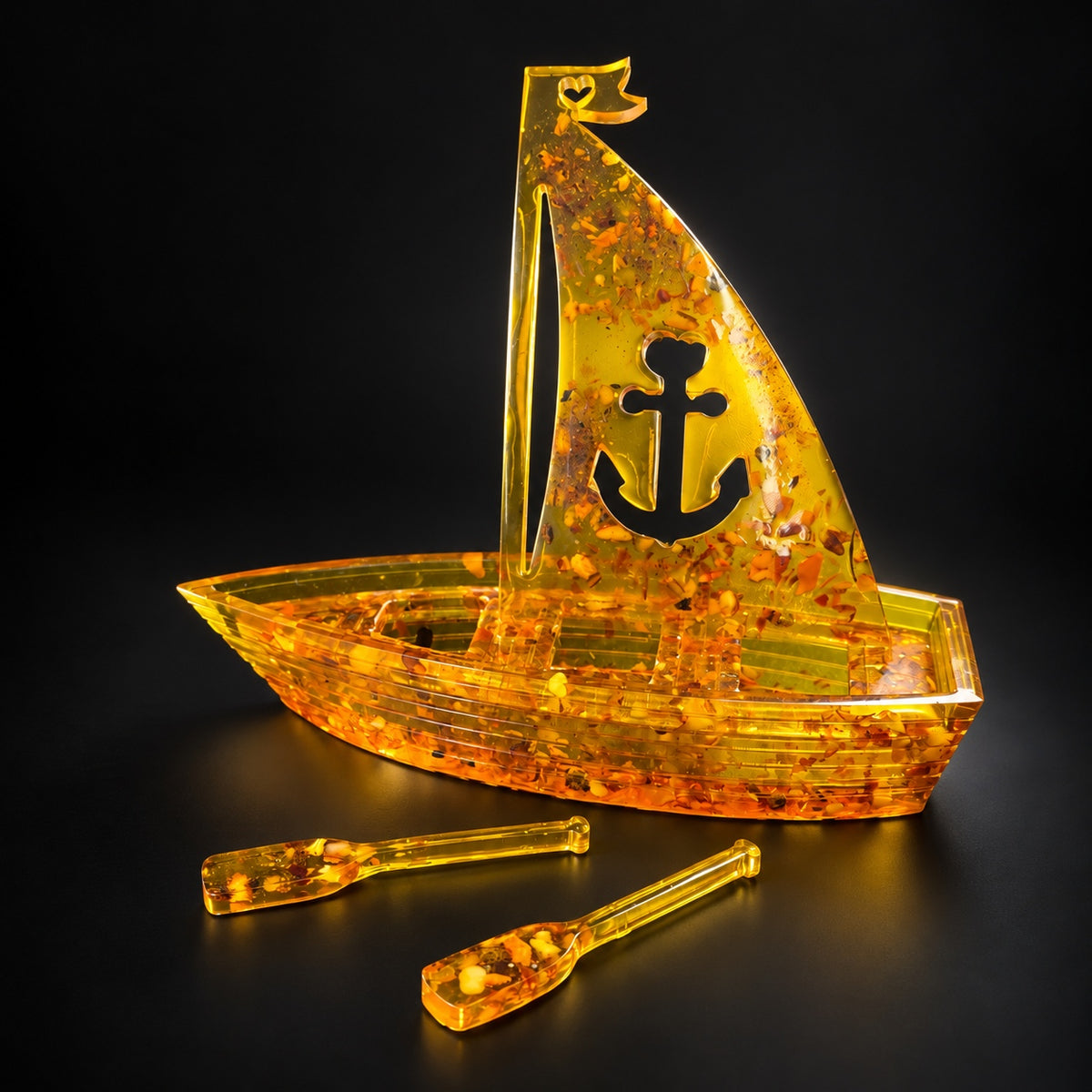 KIZIMA amber sailboat with anchor sail and two oars, illuminated against a black studio background.