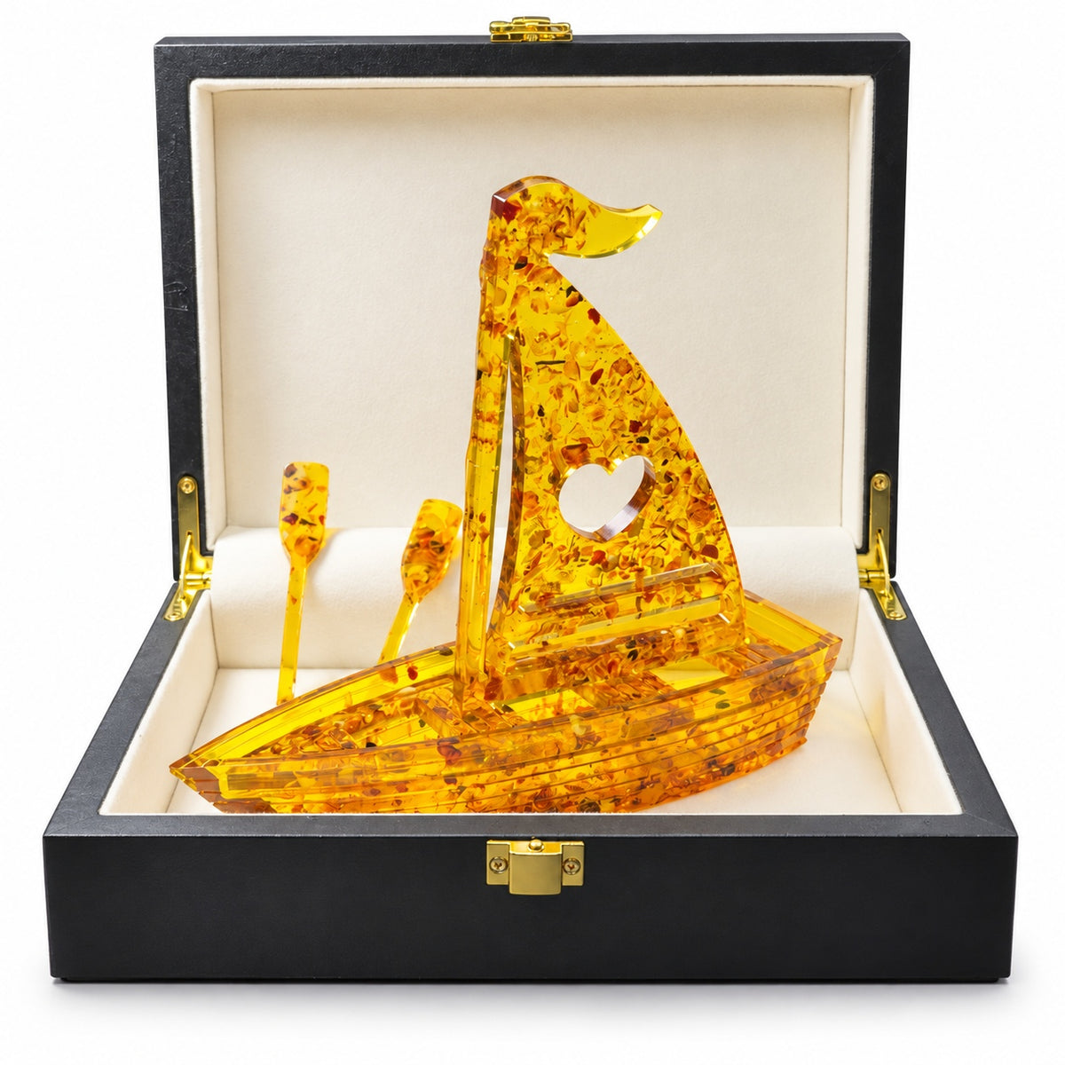 Heart-sail amber boat with two oars inside its real black presentation box with cream lining and gold clasp, on white.