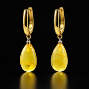 KIZIMA lemon-yellow amber teardrop earrings with gold-plated hoops and silver-tone cone connectors on black.