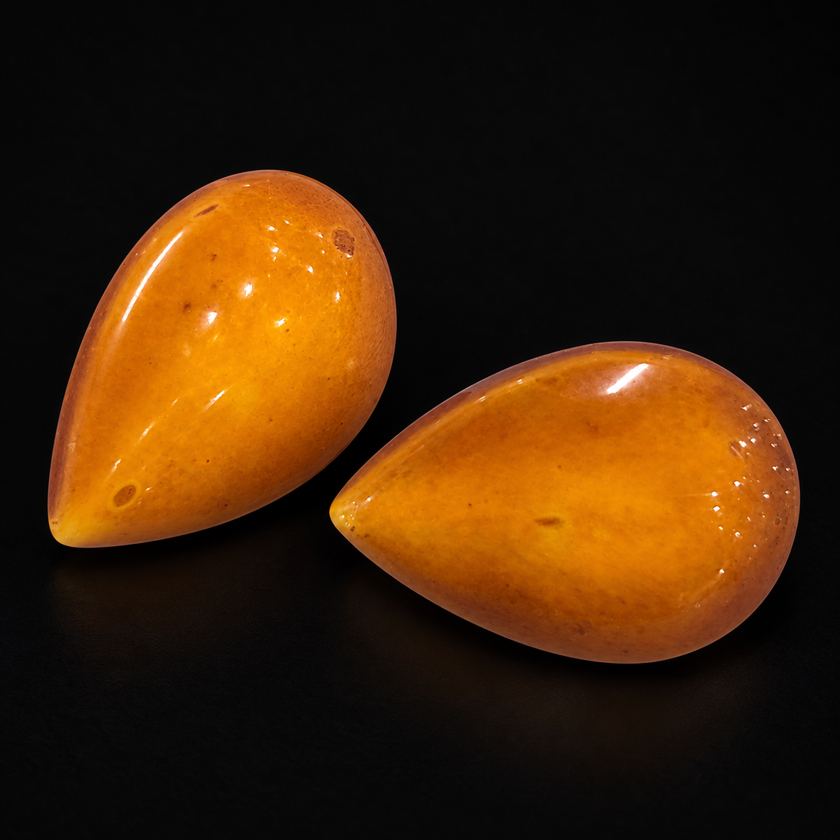 KIZIMA vintage honey-orange amber teardrop stud pair showing original inclusions and age marks on black.