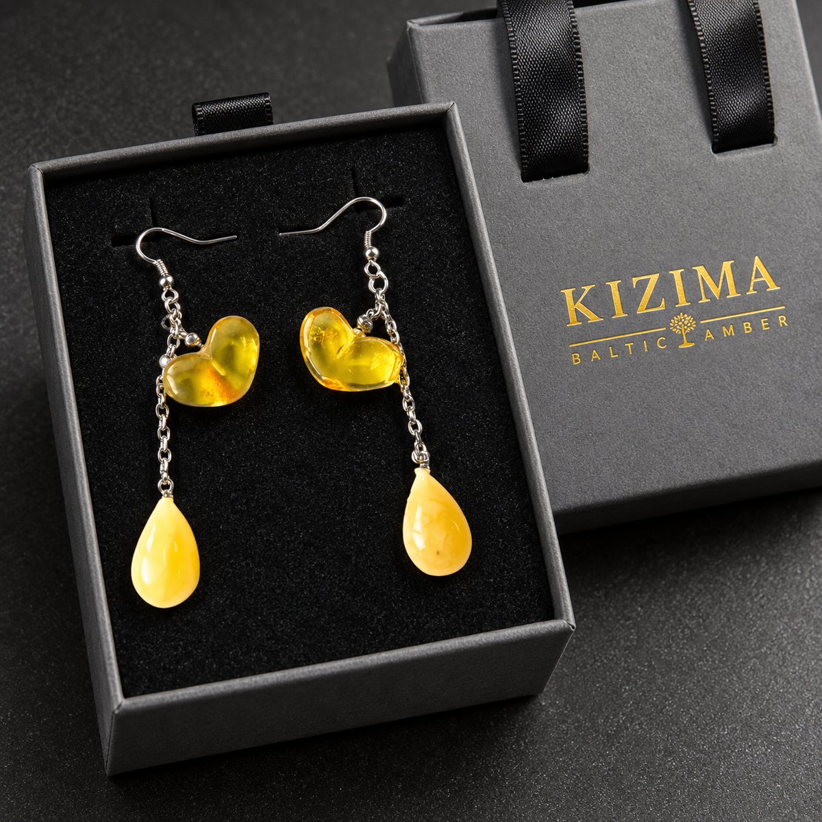 KIZIMA lemon amber heart and pale-yellow teardrop chain earrings in the gray KIZIMA Baltic Amber gift box.