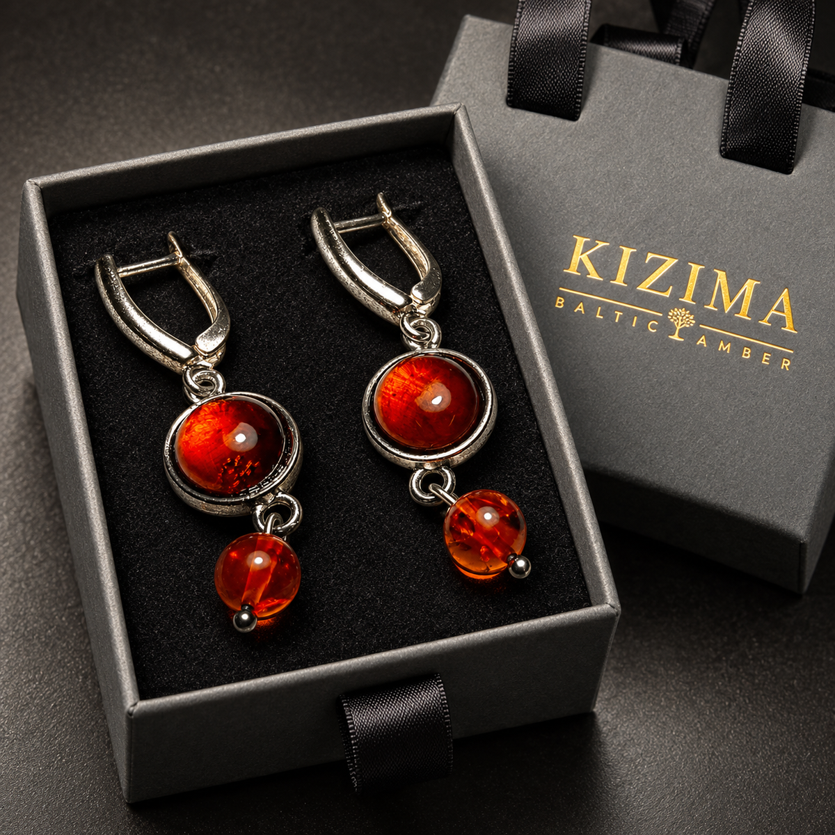 Cognac amber cabochon and ball drop earrings in a charcoal gray KIZIMA ribbon-handle gift box with black insert.
